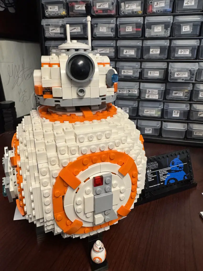 LEGO BB-8 robot model in white and orange on a desk, with a small BB-8 figure beside it